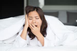 A young woman yawns after waking up in her bed