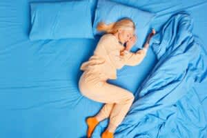 Blonde woman sleeps peacefully on side in bed.