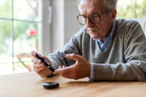 Mature man checking blood sugar level with glucometer