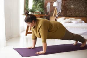 Woman holds yoga pose on a purple yoga mat