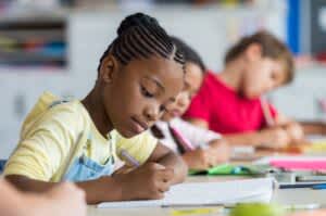 stock photo of a pupil writing at desk in classroom