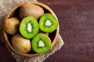 Kiwi fruit in a wooden bowl on a brown table