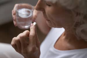 Top above view middle aged retired woman holding a pill