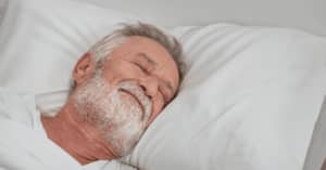 Older man sleeping in a bed.