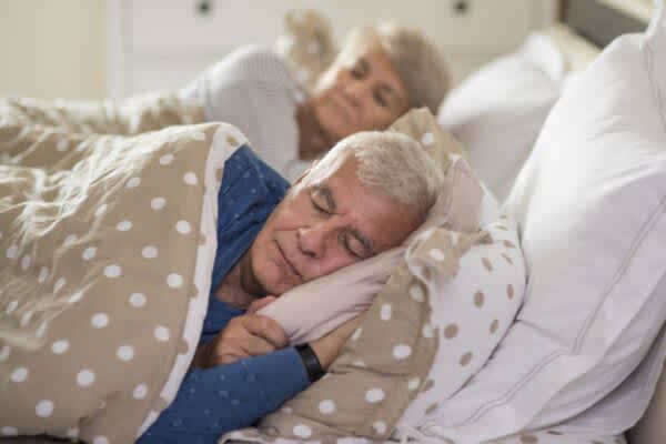 Senior couple sleeping peacefully in bed.