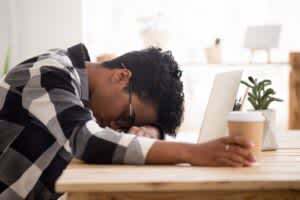 young man resting his head down on a laptop