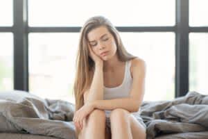 Tired young woman sitting on bed in the morning