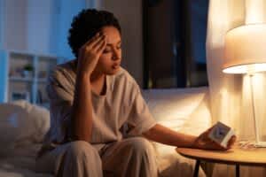 stock photo of a woman staring at a clock at night