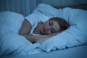 stock image of a woman sleeping in bed smiling