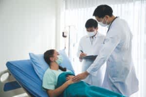 Young woman in hospital with COVID-19 speaking with doctors.