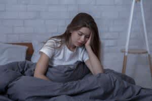 Young woman with seasonal depression sitting in bed.